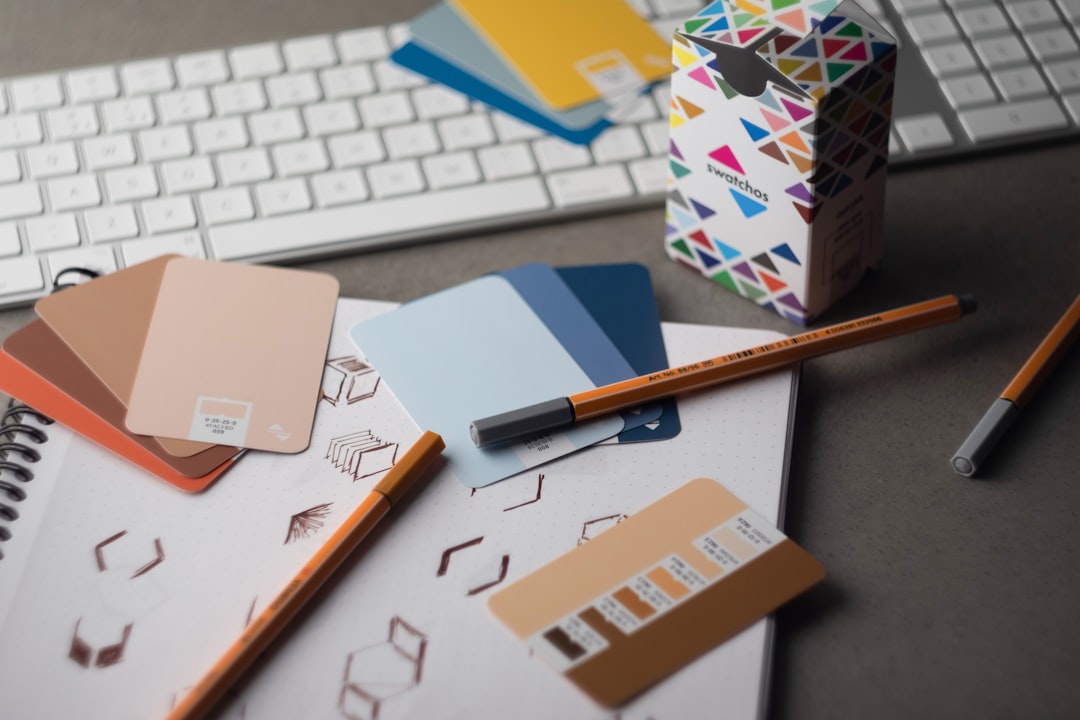 Tata letak kerja dengan keyboard, pena, dan kertas desain untuk merencanakan cetak flyer berkualitas.